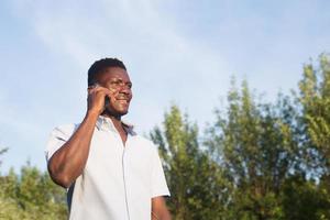 glad afrikansk amerikan med en telefon på gatan foto