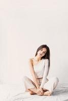 vacker ung kvinna i vita mysiga kläder som sitter på golvet foto