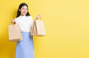 ung flicka som håller shoppingpåse med ett lyckligt ansikte på gul bakgrund foto