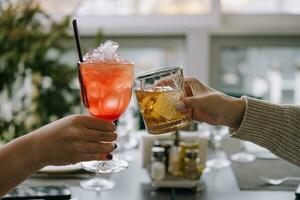 vänner toasting med glasögon av whisky och jordgubb cocktail foto