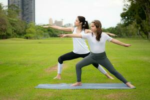 ung kvinna och liten flicka med utomhus- aktiviteter i de stad parkera, yoga är henne VALDA aktivitet. foto