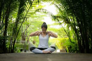 ung kvinna i de trädgård där är trä- gångvägar och en tunnel av färsk grön träd, med yoga aktiviteter för hälsa foto