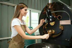porträtt av en ung kvinna arbetssätt med en kaffe rosten maskin foto