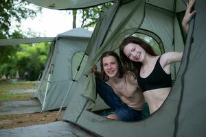 ung par camping i tält i skog leende Lycklig och avslappnad ser på kamera foto