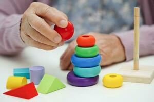 Bangkok, thailand - Maj 15, 2022 asiatisk äldre kvinna spelar rubik kub spel till öva hjärna Träning för hjälp demens förebyggande och alzheimers sjukdom. foto