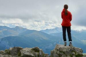 äventyrlig 13-åring flicka gazing på europeisk toppar från kulle som storm närmar sig foto