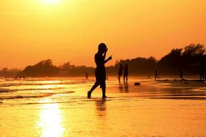 en person gående på de strand på solnedgång foto