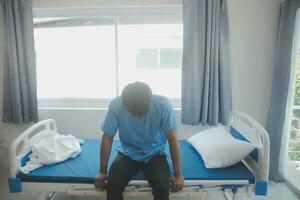 deprimerad senior man Sammanträde på de sjukhus säng ensam på natt, han känner ensam och övergiven foto