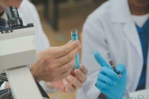 forskare eller medicinsk i labb täcka arbetssätt i biotekniska laboratorium, mikroskop Utrustning för forskning med blandning reagens i glas flaska i klinisk laboratorium. foto