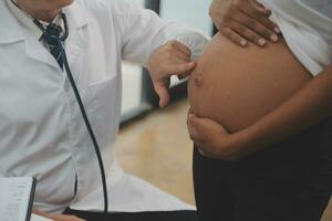 kvinna läkare är kontroll gravid kvinna med stetoskop. begrepp omtänksam för gravid kvinna foto
