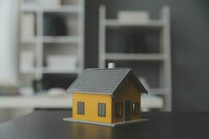 husmodell med fastighetsmäklare och kund diskuterar för kontrakt för att köpa hus, försäkring eller lån fastigheter bakgrund. foto