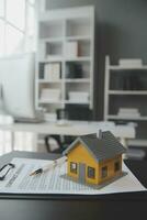 husmodell med fastighetsmäklare och kund diskuterar för kontrakt för att köpa hus, försäkring eller lån fastigheter bakgrund. foto