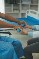 fysioterapeut man ger övning med hantel behandling handla om ärm och axel av idrottare manlig patient fysisk terapi begrepp foto