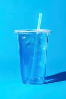 blå dryck i en plast kopp isolerat på en blå bakgrund. ta bort drycker begrepp. ai genererad foto