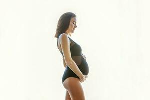 graviditet kvinna stående nära fönster på Hem och ler foto