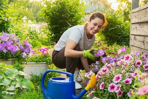 trädgårdsarbete och lantbruk begrepp. ung kvinna bruka arbetstagare trädgårdsarbete blommor i trädgård. trädgårdsmästare plantering blommor för bukett. sommar trädgårdsarbete arbete. flicka trädgårdsarbete på Hem i bakgård. foto