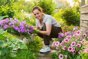 trädgårdsarbete och lantbruk begrepp. ung kvinna bruka arbetstagare trädgårdsarbete blommor i trädgård. trädgårdsmästare plantering blommor för bukett. sommar trädgårdsarbete arbete. flicka trädgårdsarbete på Hem i bakgård. foto