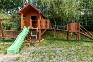 tom modern trä lekplats på grön gård i allmän park på sommardagen. roligt leksaksland för barn. urbana träningsaktiviteter för barn utomhus. stadsdel barndom koncept. foto