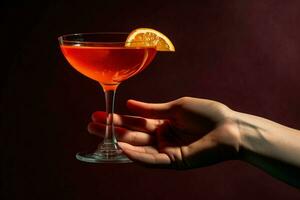 en hand innehav en röd cocktail glas med en skiva foto