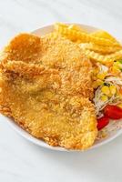 fish and chips med minisallad på den vita plattan foto