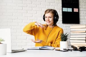kvinna i hörlurar som studerar online med hjälp av bärbar dator som talar i videochatt
