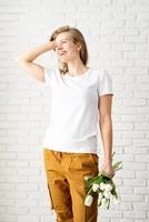 ung kvinna som bär tomma vita t-shirtinnehav tulpanblommor