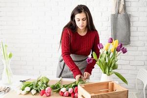 kvinna blomsterhandlare som gör en bukett med färska färgglada tulpaner