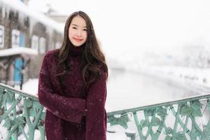 asiatisk kvinna som ler glad för att resa i snö vintersäsongen foto