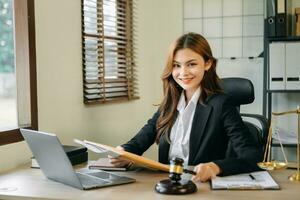 asiatisk advokat kvinna arbetssätt med en bärbar dator och läsplatta i en lag kontor. Rättslig och Rättslig service begrepp. foto
