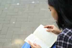 Lycklig och succes kvinna asiatisk högskola studerande njuter läsa en bok i de parkera foto