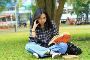 omtänksam kvinna asiatisk studerande läsning en bok och tänkande till planera en projekt foto