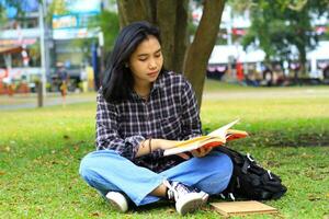 allvarlig asiatisk kvinna studerande läsa en bok tror och do forskning för henne läxa foto