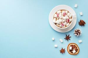 kopp av varm choklad med marshmallow kakao pulver och kola nötter, apelsiner på pastell blå bakgrund med kopia Plats. jul vinter- begrepp. foto