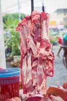 okokt rött kött som hänger på kroken på den thailändska marknaden foto