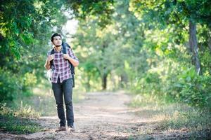 ung hipster man går på landsbygden vägen under vandringar på semester. foto