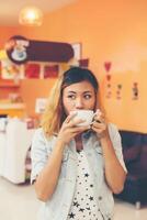 ung vacker kvinna dricka varmt cappuccino kaffe på café. foto