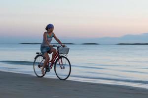 ung kvinna under en cykeltur på stranden tidigt på morgonen foto