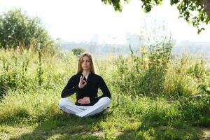 ung kvinna praktiserande yoga i de stad parkera foto