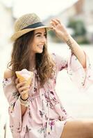 porträtt av en skön leende lady i en sommar utrusta innehav ett is grädde på en varm sommar dag foto