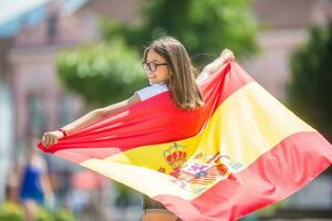 Lycklig flicka turist gående i de gata med spanska flagga foto