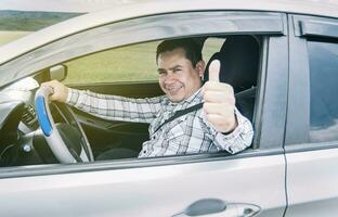 Lycklig man i hans bil ger en tummen upp, porträtt av en man som visar tummen upp medan körning, man i hans bil ger en tummen upp foto