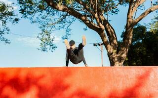 kille håller på med vägg hoppa parkour. ung man håller på med Hoppar parkour på solnedgång. konstnärlig bild av man håller på med parkour foto