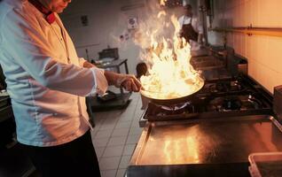 kock håller på med flambe på mat foto