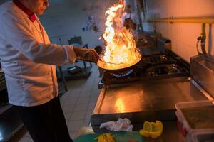 kock håller på med flambe på mat foto