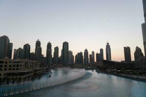 dubai sång fontäner på natt sjö se mellan skyskrapor. stad horisont i skymning modern arkitektur i uae huvudstad stadens centrum. foto