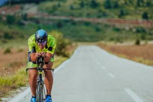 full längd porträtt av ett aktiva triathlete i sportkläder och med en skyddande hjälm ridning en cykel. selektiv fokus foto