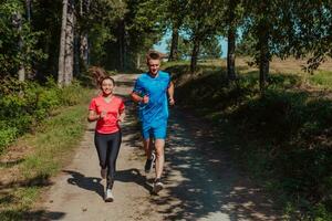 par njuter i en friska livsstil medan joggning på en Land väg genom de skön solig skog, övning och kondition begrepp foto