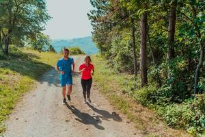 par njuter i en friska livsstil medan joggning på en Land väg genom de skön solig skog, övning och kondition begrepp foto