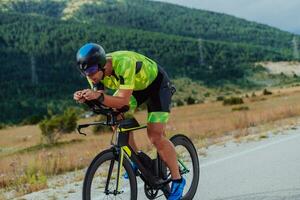 full längd porträtt av ett aktiva triathlete i sportkläder och med en skyddande hjälm ridning en cykel. selektiv fokus foto