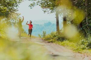 par njuter i en friska livsstil medan joggning på en Land väg genom de skön solig skog, övning och kondition begrepp foto